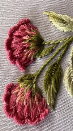 three different colored flowers on a white cloth