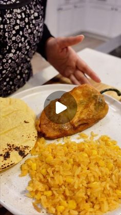 a white plate topped with food next to a tortilla and corn on top of a table