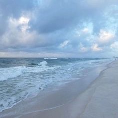 people are walking along the beach on a cloudy day