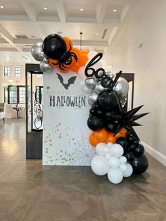 an entrance decorated with balloons and decorations for the halloween party in black, white and orange colors