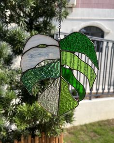 a green and white stained glass hanging from a tree