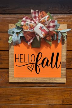 an orange sign with the word hello fall on it and a bow hanging from it