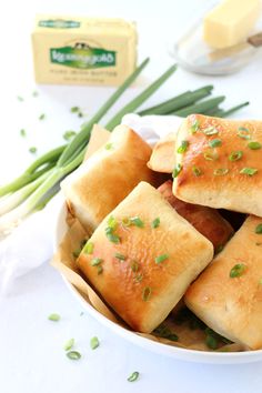 a white bowl filled with food next to green onions and cheese cubes on top of a table