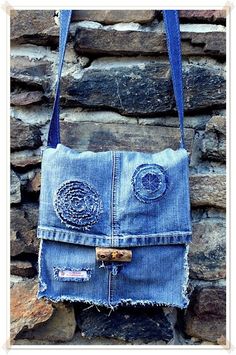 a purse made out of old jeans is hanging on a stone wall