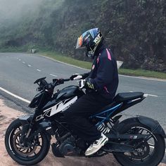 a person sitting on a motorcycle next to the road