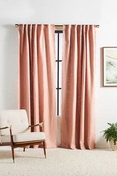 a chair sitting in front of a window with pink curtains