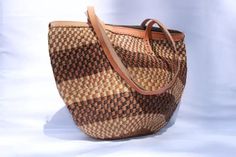 Tote bag, Woven Bag with Leather Handles, Beach Bag, Picnic Bag, Natural Bag, laptop bag, Office bag, Traveling bag This beautiful handmade Tote bag originated from craftsmen living in Eastern Community in Kenya, the Akamba. Our Tote bags are woven using colored sisal and leather hands.The woven bag is made from products which are entirely eco-friendly and sustainable, leather to provide comfort and padding. Leathers are naturally tanned from cows and camel. It has a zipper. This Tote bag is really stylish, functional and eco-friendly for everyday use, summer travels and beyond. From travel to work or a night out, makes it easier to fill your closet with ethical, high quality staples for every occasion. It's dimensions are approximately; 12" Widh  x 12" Height (excluding the handle). T.hey Eco-friendly Woven Shoulder Bag For Travel, Rectangular Travel Bag With Weaving, Eco-friendly Woven Beach Bag For Travel, Rectangular Woven Travel Bag, Travel Shoulder Bag With Weaving Details, Weaving Shoulder Travel Bag, Daily Use Shoulder Bag With Weaving, Woven Bucket Bag Tote, Woven Tote Beach Bag For Travel