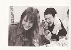 two women laughing while sitting at a table