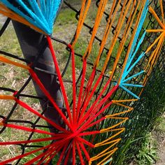 several colored sticks sticking out of the side of a metal fence on top of grass