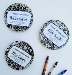 three black and white coasters with two crayons next to each other on a table