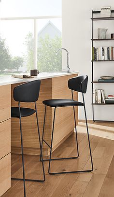 two black chairs sitting on top of a hard wood floor next to a countertop