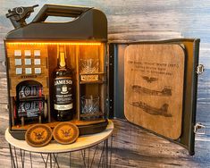 an open suitcase filled with liquor bottles on top of a white table next to a wooden wall