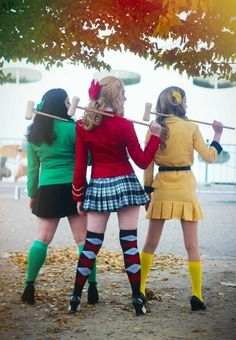 three women dressed in costumes are standing under a tree with their backs to the camera