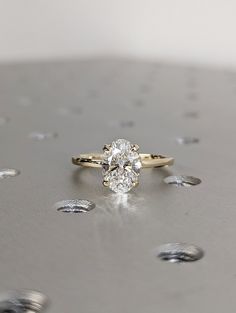 a diamond ring sitting on top of a metal surface with drops of water around it