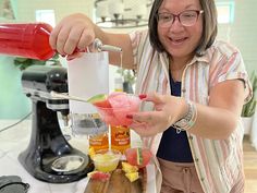 a woman is making a drink in a blender with fruit on the rims