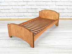 a small wooden bed frame sitting on top of a hard wood floor next to a brick wall