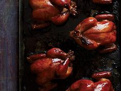 two whole chickens sitting on top of a baking pan covered in brown sauce and ketchup