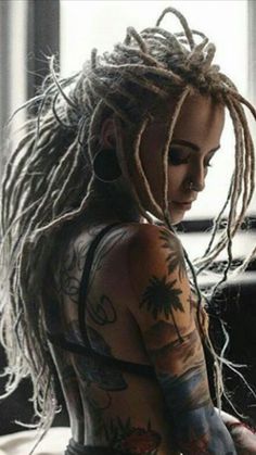 a woman with dread locks and tattoos on her body