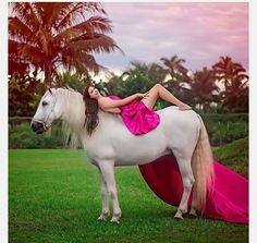 a woman in a pink dress is sitting on a white horse with her legs spread out