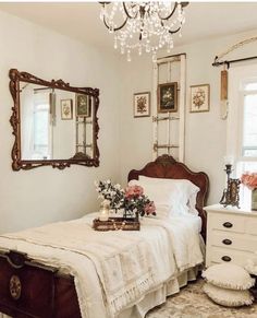 a bedroom with a bed, dresser and chandelier hanging from it's ceiling