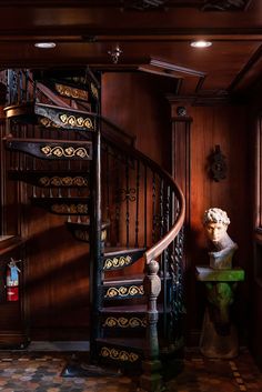 a spiral staircase in a house with wood paneling and iron railings on either side