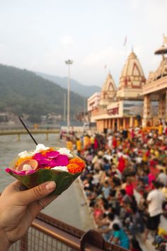 a person holding up a small bowl with flowers in front of a large group of people