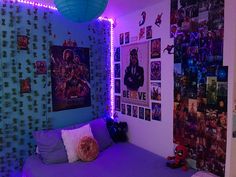 a bed with purple sheets and pillows in a room filled with posters on the wall