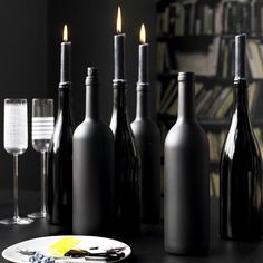 wine bottles and glasses are sitting on a table next to each other with candles in them