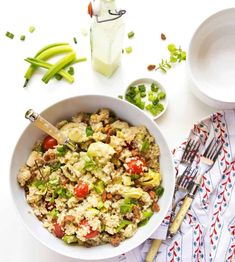 a white bowl filled with rice and vegetables next to two bowls of peas, celery