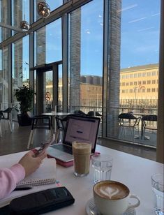 a woman sitting at a table with a laptop and cup of coffee in front of her