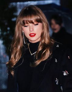 a woman with long hair and red lipstick wearing a black outfit, holding an umbrella