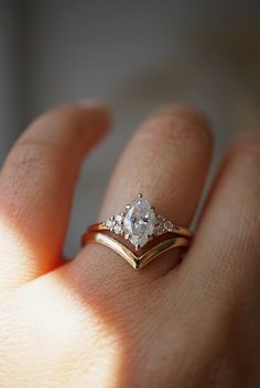 a woman's hand holding a gold ring with two diamonds on top of it