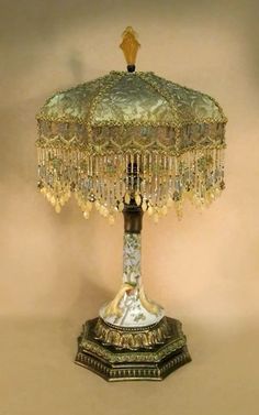 an ornate lamp is on display against a beige background with gold trimmings and beads