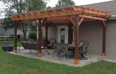 a covered patio with chairs and tables in front of a house on a lawn area