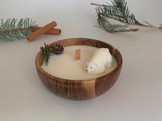 a wooden bowl filled with a candle and a small white polar bear on top of it