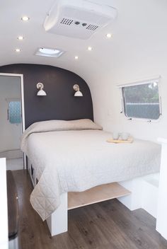 a bed sitting in the middle of a room next to a window and ceiling fan