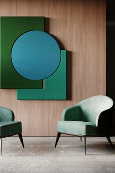 two green chairs sitting next to each other in front of a painting on the wall