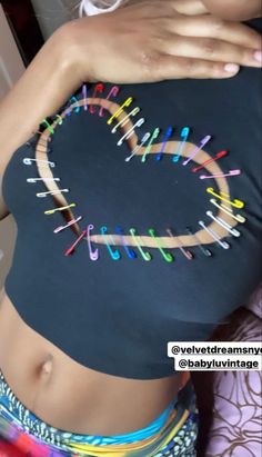 a woman wearing a black top with colorful pins attached to her chest and the words love is written on it