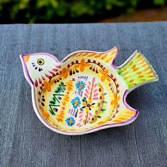 a colorful bird shaped dish sitting on top of a table