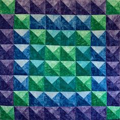 a blue and green quilt with many different colors on it's sides, including triangles