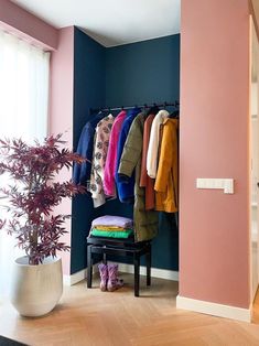 an open closet with clothes hanging on the wall and a bench in front of it