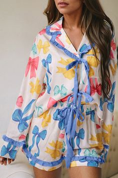 Embrace your inner elegance with our Bow Print Tied Ruffled Pajama Set, a delightful blend of comfort and Southern Belle charm. Perfect for cozy spring mornings or relaxing at home, this pajama set combines playful bow prints with delicate ruffle... Cute Floral Print Sleepwear For Pajama Party, Printed Blue Sleepwear For Spring, Blue Printed Sleepwear For Spring, Cute Floral Print Sleepwear For Spring, Spring Sleepwear With Ruffles, Cute Ruffled Sleepwear For Spring, Feminine Blue Sleepwear For Pajama Party, Cute Ruffled Sleepwear For Loungewear, Spring Ruffled Pajamas For Pajama Party