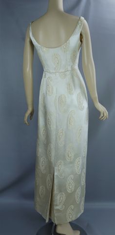 1960's gold jacquard evening gown. Low scoop neck, set in waist, column skirt with a side metal zipper closing and a long closed back pleat. Sleeveless vest style jacket with a cuff collar that closes in the front with a large covered button. Waist is very high so it could have been styled as an empire waist. Both pieces are completely lined.There are some condition issues. A large spot of soiling on the hem which I have photographed closely. The fabric has some fabric scratches on the bodice and a few places on the skirt. Label is Starke of London which is the designer and Madame Runge which was an upscale retail shop on South Granville Street in Vancouver, from the late thirties until the seventies. Please check the measurements carefully. Keep in mind there is no give to this fabric.Gow Vintage Brocade Fitted Dress, Fitted Vintage Brocade Dress, 1960s Dresses Formal, 50s Formal Dress, Gown With Jacket, 1960s Dresses, Formal Evening Gown, Column Skirt, Vest Style