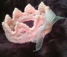 a crocheted pink and white tiara on a black blanket with a bow