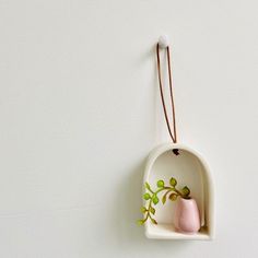 a ceramic vase hanging on the wall with a string attached to it's side