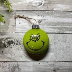 a green christmas ornament with a grin face drawn on it's side