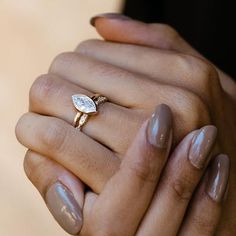 a woman's hand holding a ring with a diamond on the middle and two fingers