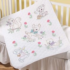 a crib bed with a baby blanket and stuffed animals on it's side