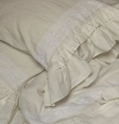 an unmade bed with white linens and ruffled edges on top of it