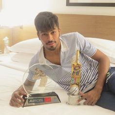 a man sitting on top of a bed holding an award in front of his face